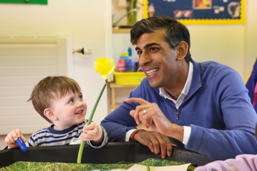 Prime Minister Rishi Sunak smiles as he plays with child in nursery